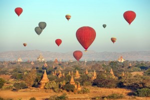 Multicolored hot air balloons over Buddhist temples at sunrise. Bagan, Myanmar.